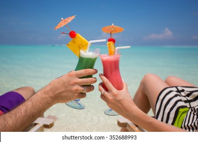 Hands with colorful cocktails on the beach. 