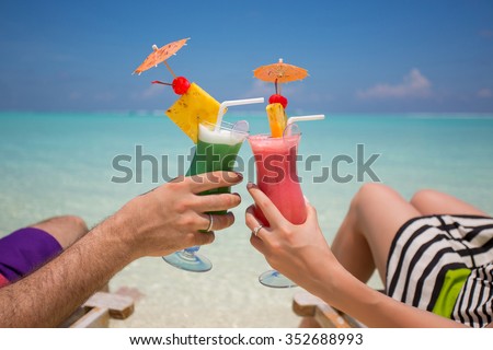 Hands with colorful cocktails on the beach. 