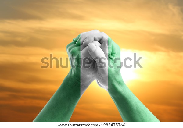 Hands in colors of\
Nigerian flag at sunrise