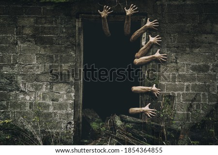 Hands coming out from the door with dark background. Scary zombie hands.