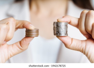 Hands compare two piles of coins of different sizes. - Shutterstock ID 1942178725