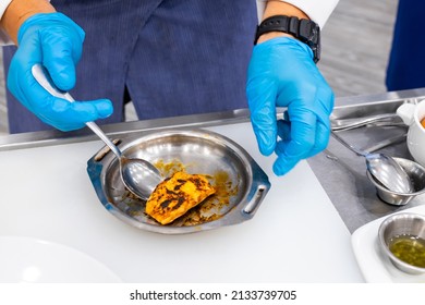 The Hands Of The Cook In Blue Gloves Fry The Fish In A Plate. Novice Cook