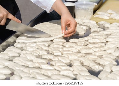 Hands Of The Cook With A Large Kitchen Knife Cut Dough Pieces For Frying On A Street Food Tray