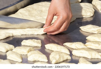 Hands Of The Cook With A Large Kitchen Knife Cut Dough Pieces For Frying On A Street Food Tray. Close-up