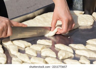 Hands Of The Cook With A Large Kitchen Knife Cut Dough Pieces For Frying On A Street Food Tray. Close-up