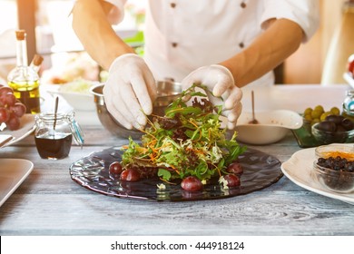 Hands Of Cook Making Salad. Salad Pile On A Plate. Tasty Salad With Arugula. Sliced Grape And Carrot.