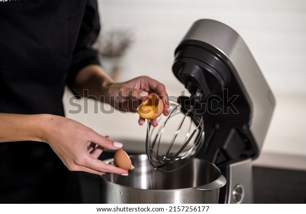 hands of a\
cook near a food processor break an\
egg