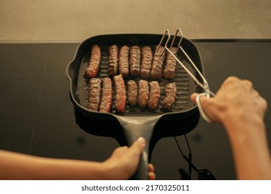 Hands cooking 
cevapi - fresh minced meat in grill pan cooking bbq lunch with hands