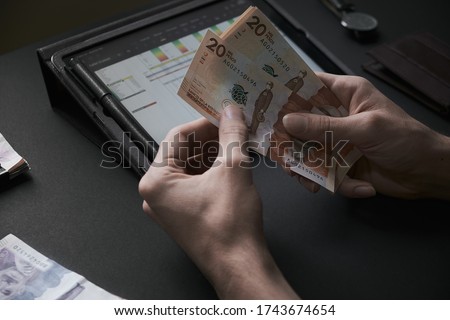 Man´s hands counting a group of 20000 colombian pesos bills on a dark office background