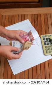 Hands Counting Small Money Next To Calculator