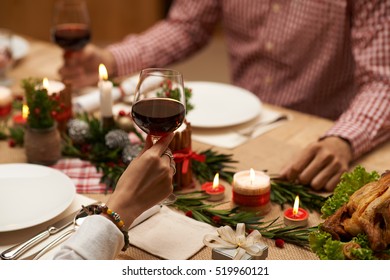 Hands Of Couple Drinking Red Wine At Christmas Table