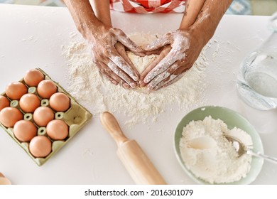 Hands of couple kneading dough at kitchen.