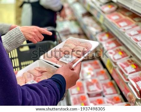 Hands of a couple who choose meat at the supermarket