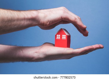 Hands Covering A Toy House. Home Protection Concept