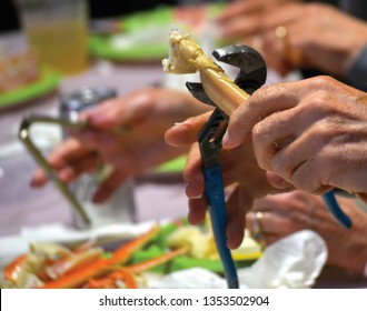 Hands Cracking Crab Legs With Pliers