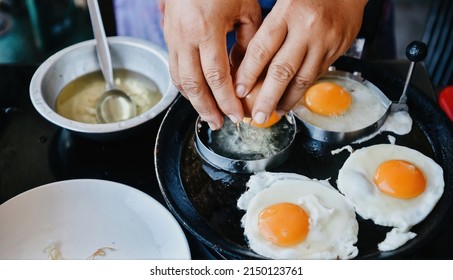 Hands Cracking Eggs Into A Heated Pan Mold. To Prepare Fried Eggs.