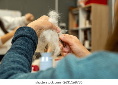 Hands crafting wool in workshop setting.