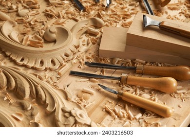 Hands of craftsman carve with a gouge in the hands on the workbench in carpentry. Wood carving tools close-up top view. - Powered by Shutterstock