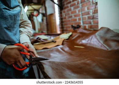 Hands of craftswoman cutting while working at table in leather fabric in studio - Powered by Shutterstock