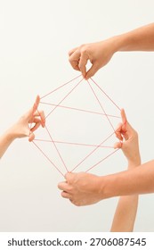 Hands creating a geometric pattern by pulling red string in a playful activity