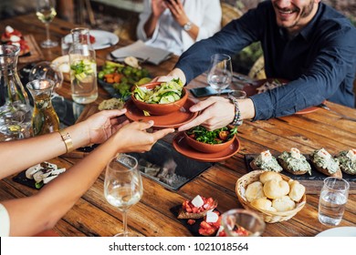 Hands of cropped unrecognisable woman and man passing salad bowl at vegetarian restaurant. - Shutterstock ID 1021018564