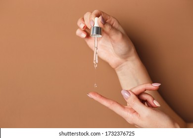 Hands of cropped white woman holding cosmetic serum pipette on the orange background. - Shutterstock ID 1732376725