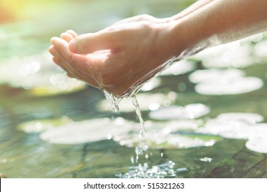 Hands in cupped form getting water from a lake or fountain - Powered by Shutterstock