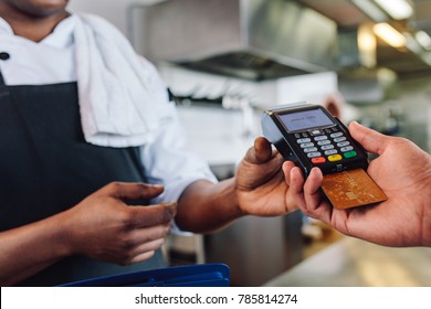 Hands Of Customer Paying Restaurant Bill Using Credit Card. Customer Making Payment Through Credit Card At Counter In A Restaurant.