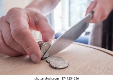 Hands cut dollar coins with a knife, separating them like pieces of food on a cutting board. Concept of taxes, fraud or profit. - Powered by Shutterstock