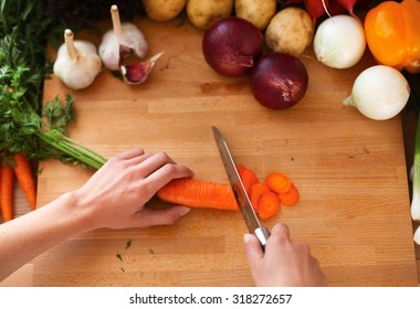 Hands Cutting Carrots On A Cutting Board.