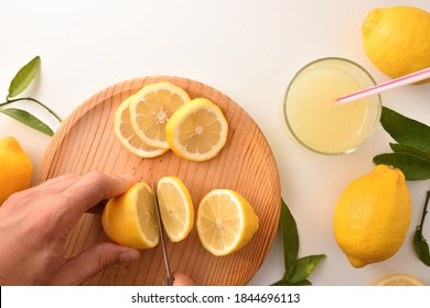 Hands Cutting A Lemon To Prepare A Lemonade On The Kitchen Bench. Top View. Horizontal Composition.