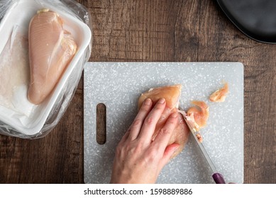 Woman’s hands cutting up raw chicken, gray cutting board, chef knife, black plate, wood table
 - Powered by Shutterstock