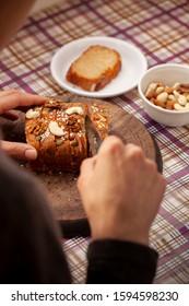 Hands Cutting Sweet Bread Cake Into Slice Through Knife On Wooden Board.