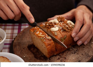 Hands Cutting Sweet Bread Cake Into Slice Through Knife On Wooden Board.