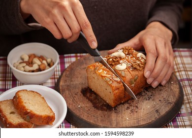 Hands Cutting Sweet Bread Cake Into Slice Through Knife On Wooden Board.