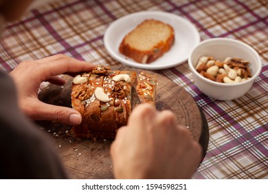 Hands Cutting Sweet Bread Cake Into Slice Through Knife On Wooden Board.