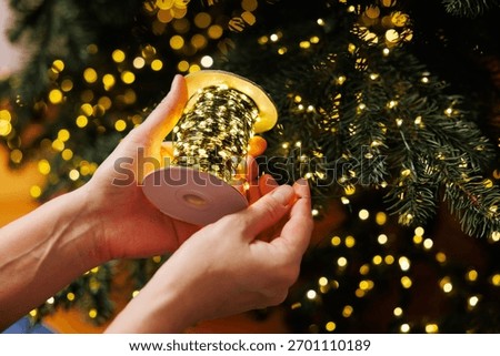Hands Decorating Christmas Tree with String Lights