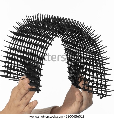 Hands demonstrating a flexible black plastic anti-cat spike mat isolated on white background for humane garden and furniture protection