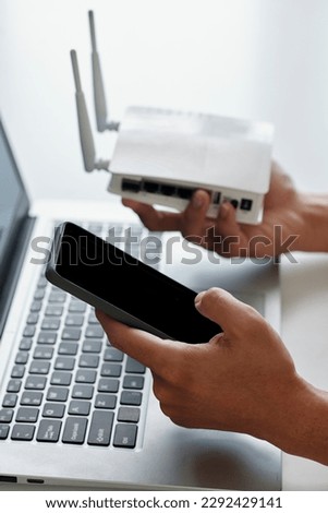 Hands of developer connecting smartphone to wi-fi router via application