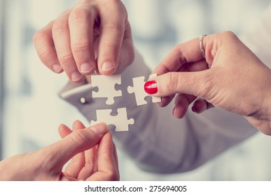 Hands Of Different People Matching Together Three Complementary Puzzle Pieces, Concept Of Unity And Problem Solving, Close-up With Retro Filter Effect.