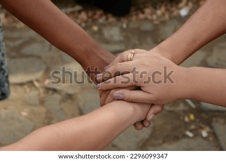 Hands of different races, different skin color, one on top of the other, intertwined, unity and strength to the same side. Only one. Unity