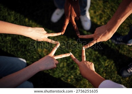 Hands of different skin tones create peace signs on grass, emphasizing togetherness and harmony in a natural outdoor environment