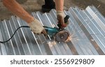 hands in dirty gloves with a grinder sawing a sheet of silver metal with a relief surface, sawing iron material with a grinder with a sparking tool