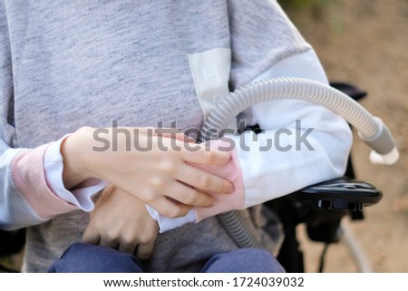 Hands of a disabled person with muscular dystrophy holding a ventilator for deep breathing, concept, background