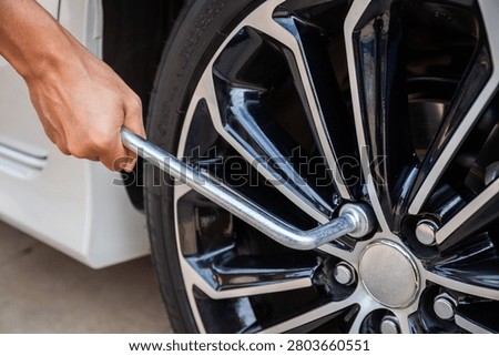 Hands disassembling a modern car wheel steel rim with a lug wrench for change wheel or repair and maintenance