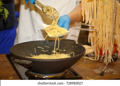 Hands In Disposable Blue Gloves Putting Spagetti On A Paper Plate. Cooking Spagetti. Fast Food