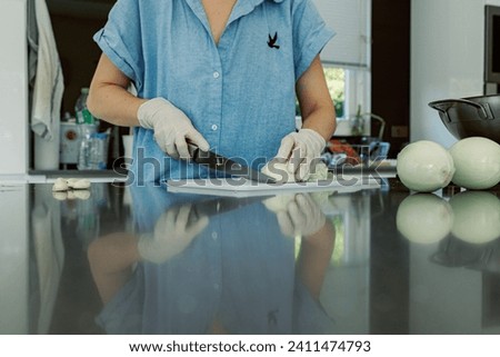 Hands in disposable gloves. Woman cooking at kitchen. Everyday routine housekeeping. Cropped image