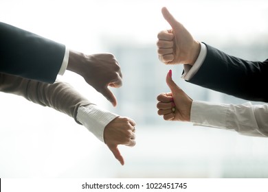 Hands of diverse business people showing thumbs up and down, like versus dislike gesture, positive negative feedback, yes and no opposition voting, confrontation disagreement at negotiations concept - Shutterstock ID 1022451745