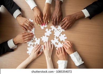 Hands Of Diverse People Connecting Puzzle Together On Office Desk, Multi-ethnic Team Engaging In Finding Best Business Solutions For Successful Teamwork, Teambuilding Unity Concept, Top Close Up View