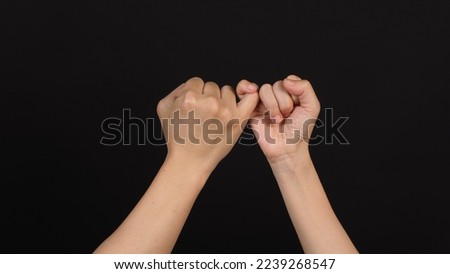 Hands is do a pinky promise gesture on black background